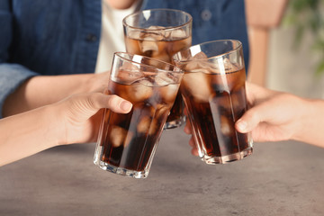 Friends with glasses of tasty refreshing cola at table, closeup view