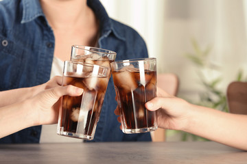 Friends with glasses of tasty refreshing cola at table, closeup view