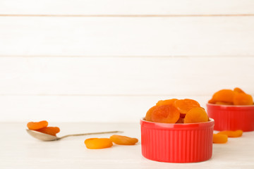 Red bowl with dried apricots on table, space for text. Healthy fruit
