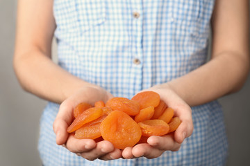 Woman holding handful of dried apricots, closeup. Healthy fruit