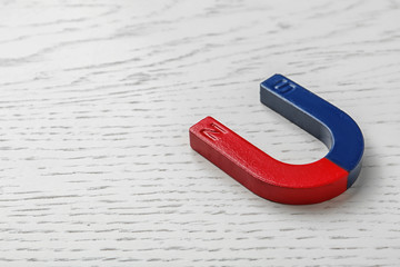 Red and blue horseshoe magnet on wooden background. Space for text