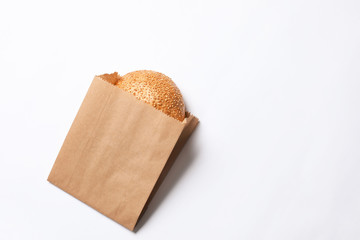 Paper bag with sesame bun on white background, top view. Space for text