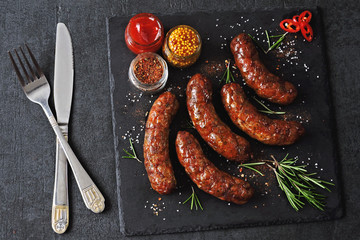 Grilled juicy Munich sausages with spices on a black stone board. Bavarian grilled sausages...