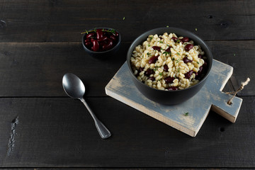 Pearl barley porridge in a plate on a black wooden background