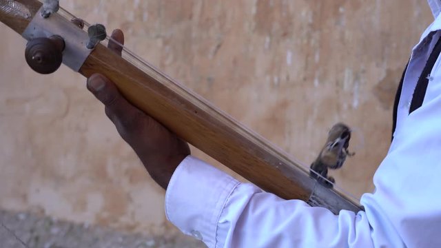 Indian musician play on traditional music instrument called Kamaycha for tourists on the road on Amber Fort in the old city of Jaipur, Rajasthan, India