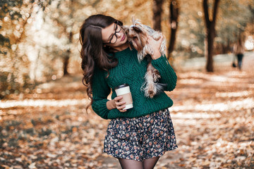 Beautiful woman walk with dog and drink coffee in the park.
