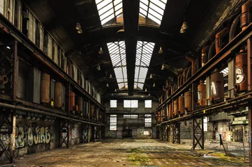Fotobehang Symmetrisch zicht op een verlaten en vervallen fabriekshal met glazen dak © Octavian