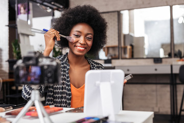 Positive dark-skinned woman with curly hair smiling brightly