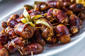 Date friut with bacon arranged on a white porcelain plate