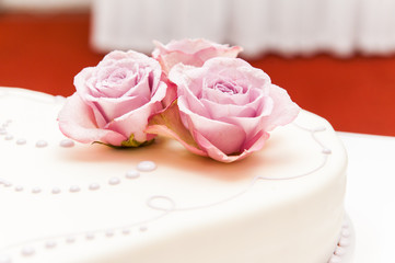 Fototapeta premium Three pink roses made of sugar on a wedding cake