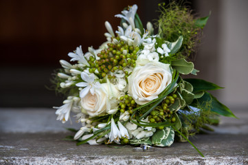 Wedding rings and a flower bouquet on granite