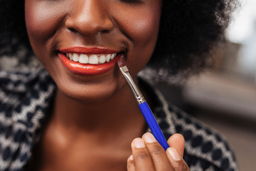Amazing african american woman with curly hair enjoying makeup process