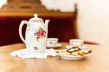 Porcelain tea set on a wooden table with bisquits