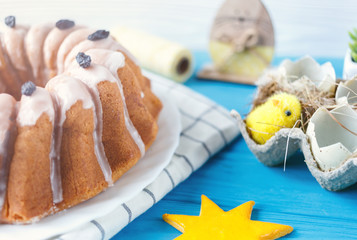 Happy Easter! Handmade cake on towel, eggs, wooden bunny rabit on white wooden background. Decoration for Easter holiday