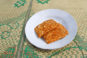 Two pieces of Tempeh Goreng in a plate on the straw mat at Yogyakarta, Indonesia