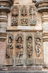 Belur, Karnataka, India - November 2, 2013:  Chennakeshava Temple. Large Brown wall stone side panel sculpture of, top row, Vishnu and his two wives, bottom row, Shilabalikas, dancing girls.
