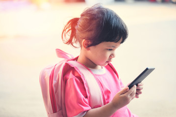 Children Playing Smartphone / child girl hold telephone in hand watching cartoons at the school