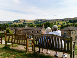 An elderly couple snuggling together on a bench, enjoying their retirement in the Yorkshire Dales