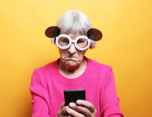 Fototapeta premium old grandmother is talking to her grandchildren by phone, smiling and greeting them.