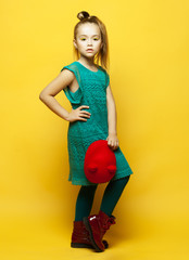 little fashion girl with blond hair posing over yellow background