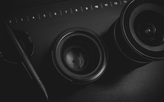 Camera lenses and graphics tablet in low key monochromatic.