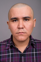 Obraz premium Young bald Asian businessman against gray background