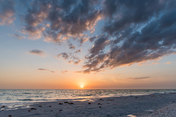 Naklejka na ściany i meble Sweeping Florida beach clouds over low tide with soft peach sunset 