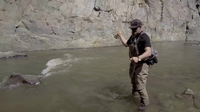 Fly fisherman walking upstream in Big Thomson River Colorado.