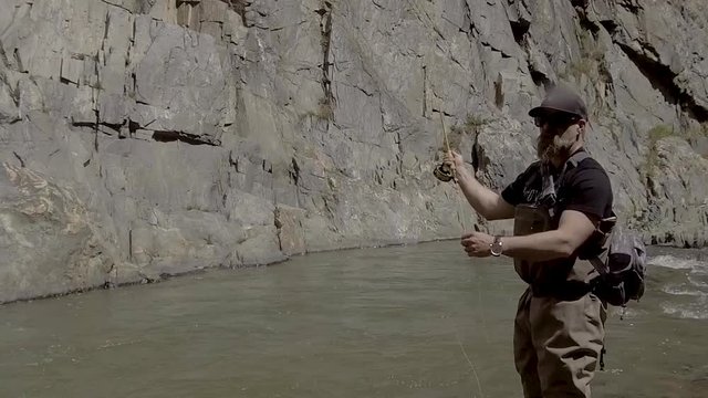 A fly fisherman casts forward and then mends the line in this slow motion shot.