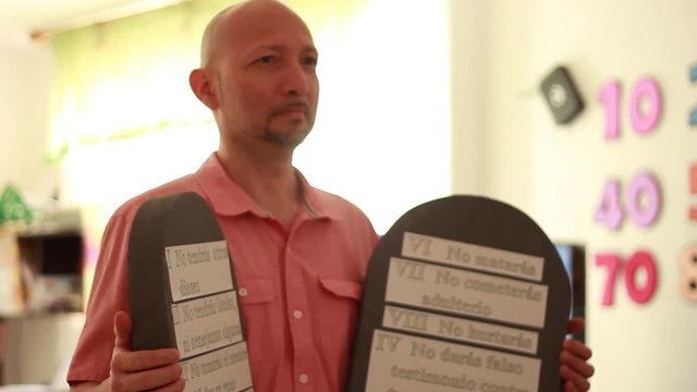 Ten Commandments cardboard tablets held by man at a religious event
