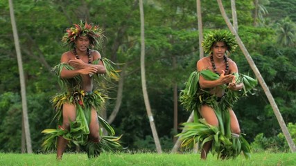 Strong young synchronized Polynesian male dancers entertaining in traditional costume barefoot outdoor French Polynesia South Pacific