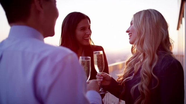 Group of multi ethnic managers toasting with champagne on rooftop at sunset