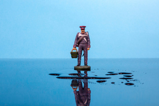 Tin soldier in the form of the Napoleonic Wars with a bucket stands in front of a puddle of water