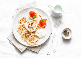 Gluten free rice flour pancakes and boiled eggs with red caviar - delicious breakfast, brunch on a light background, top view