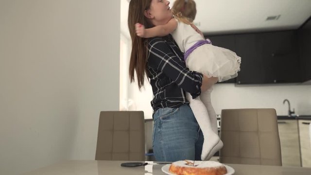 While holding a baby girl, the mother talks with her and smiles. At the end the daughter does not want to hug anymore. It is a very warm moment between the mother and daughter.