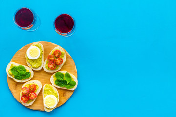 Healthy snacks. Set of toasts with vegetables like avocado, guacamole, rocket, cherry tomatoes on blue background top view copy space