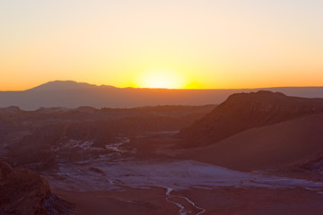 Bright hues of sunset over distant mountains ridge in Atacama Desert, Chile, South America. Panorama of high altitude desert during spectacular sunset.