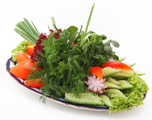 Beautifully served fresh vegetables on a plate with an ornament on a white background.