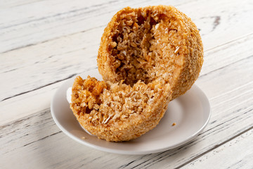 traditional Chinese fried sesame ball with one cut out on white wood table