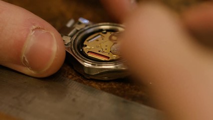 Watch maker removing battery from a wrist watch
