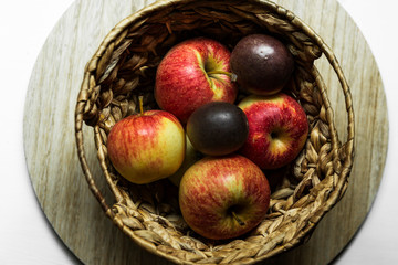 Basket of apples on table top with window light pouring through the glass.