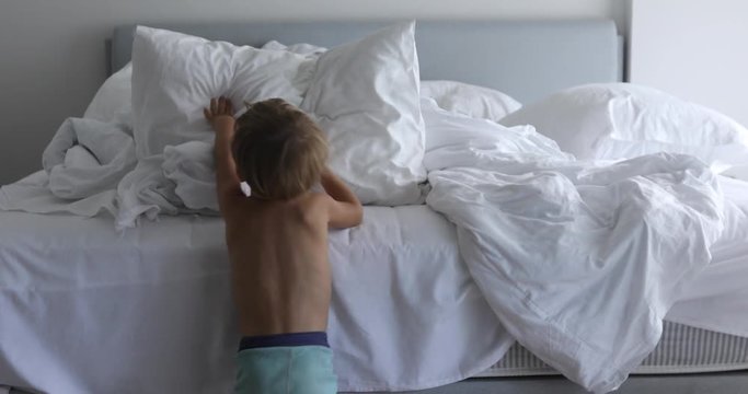 Kid is trying to make bed clean. Child making bed in room after wake up