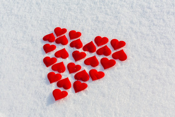 Many red hearts in a shape of big heart on glittering snow. Vilentine's day theme.