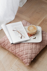 Coffee on a pink velvet cushion with an opened magazine