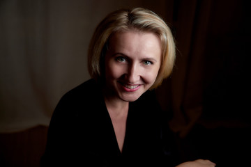 Portrait of a middle-aged woman in the room. Photography in the Studio. Photo shoot in a dark key