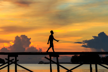 silhouette kids walk on the wooden jetty during sunset at Mantanani Island, Kota Belud, Sabah, Malaysia