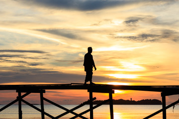 silhouette kids walk on the wooden jetty during sunset at Mantanani Island, Kota Belud, Sabah, Malaysia