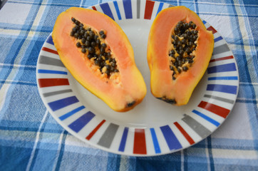 Papaya fruit on on the plate. Slices of sweet papaya on wooden background, Halved papayas with leaves,