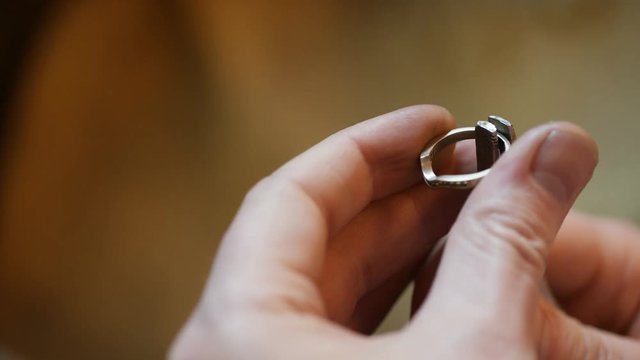 Hands of a jeweler testing the strength of a ring with some pliers