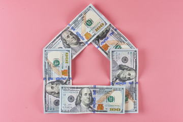 Dollars. American money in the shape of a house on a pink background. Real estate loan concept